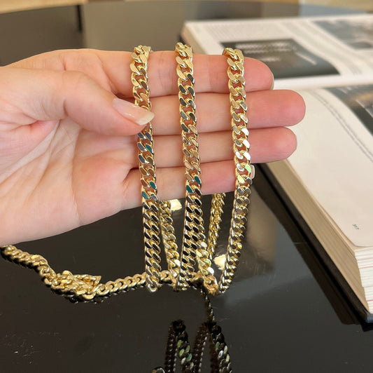 Close-up detail of 7mm gold curb chain showing texture and shine of flattened links