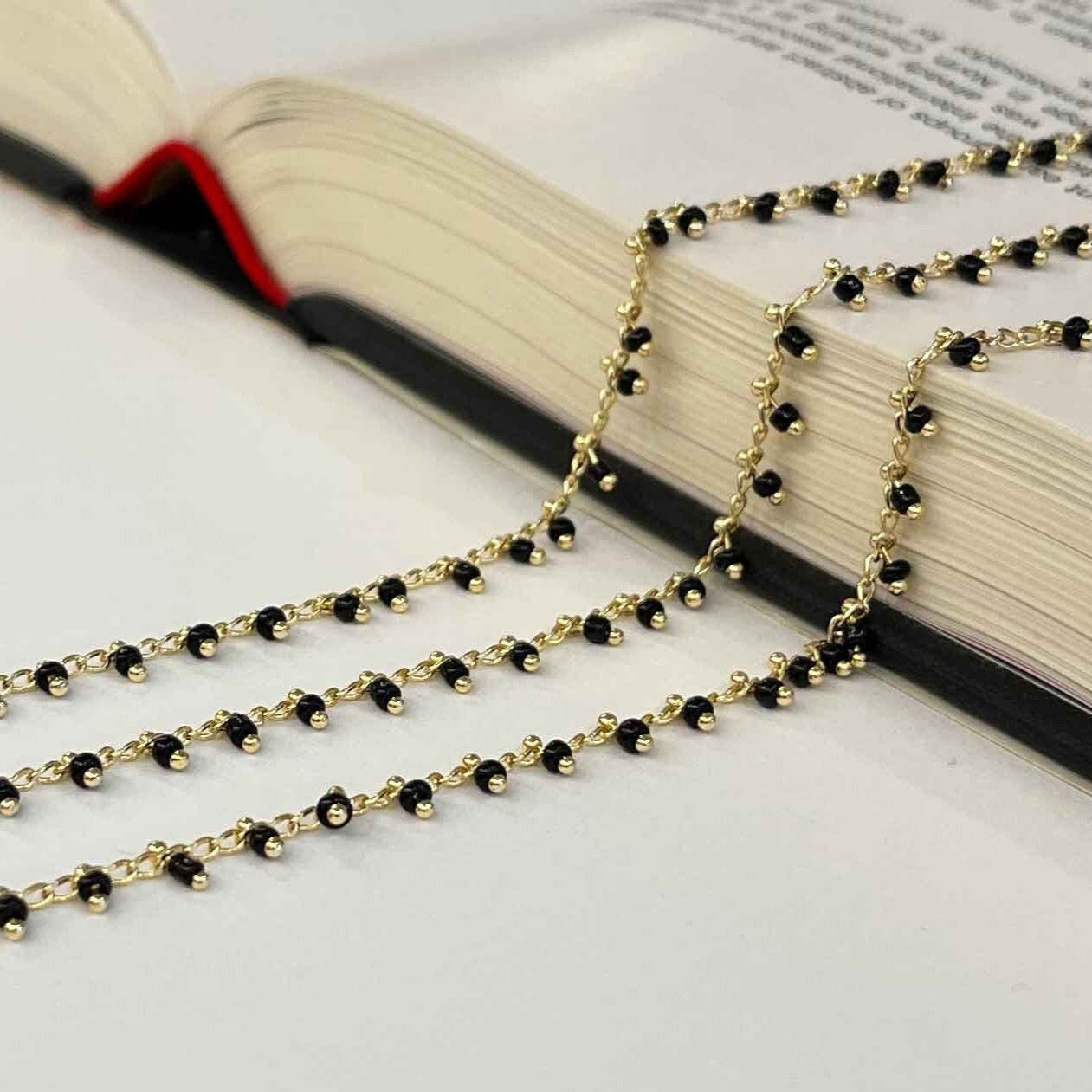 Gold and black beaded necklace on an open book