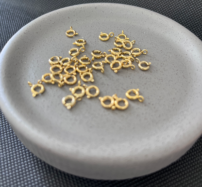 Gold jewelry charms on a gray stone surface