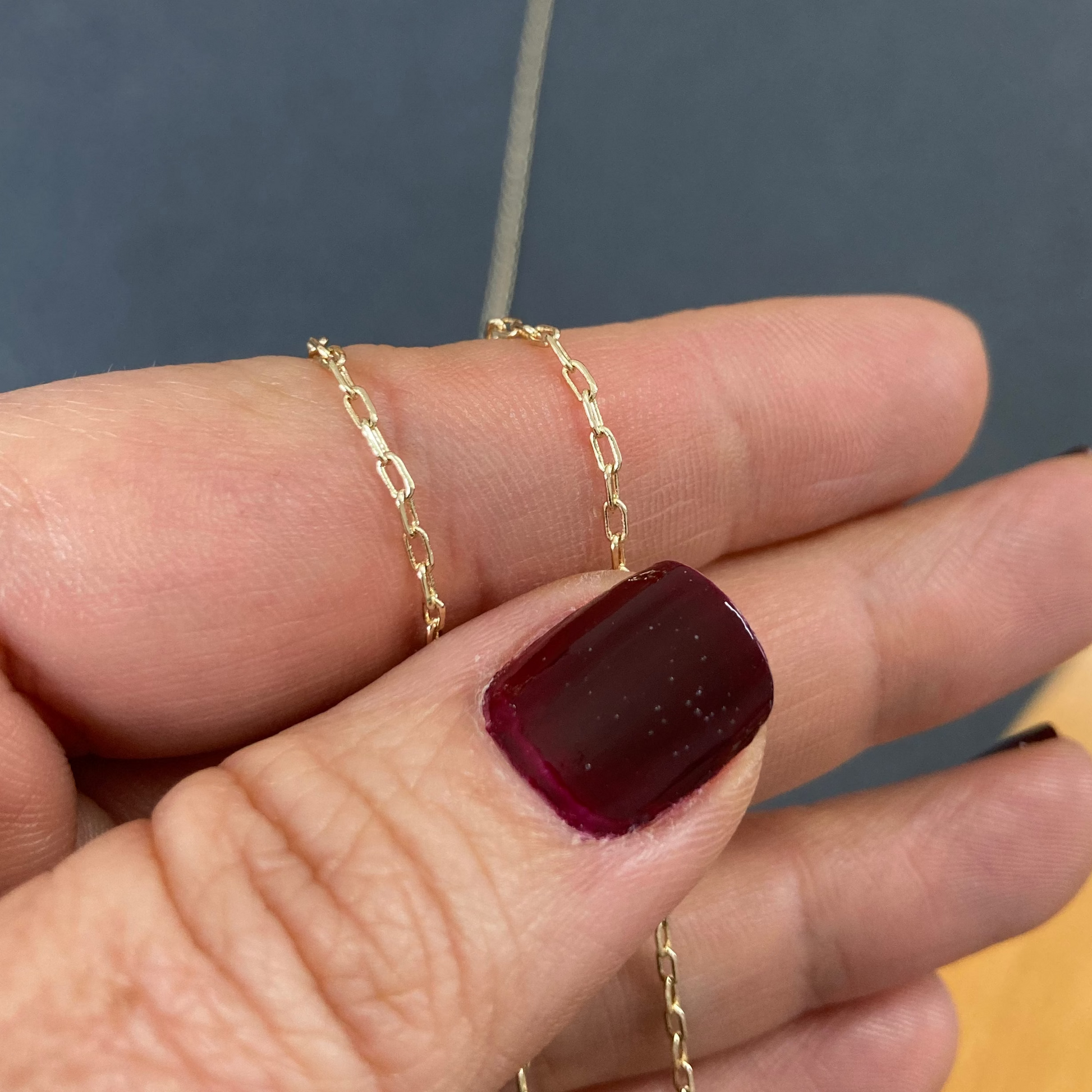 Gold chain necklace on a finger with a blurred background