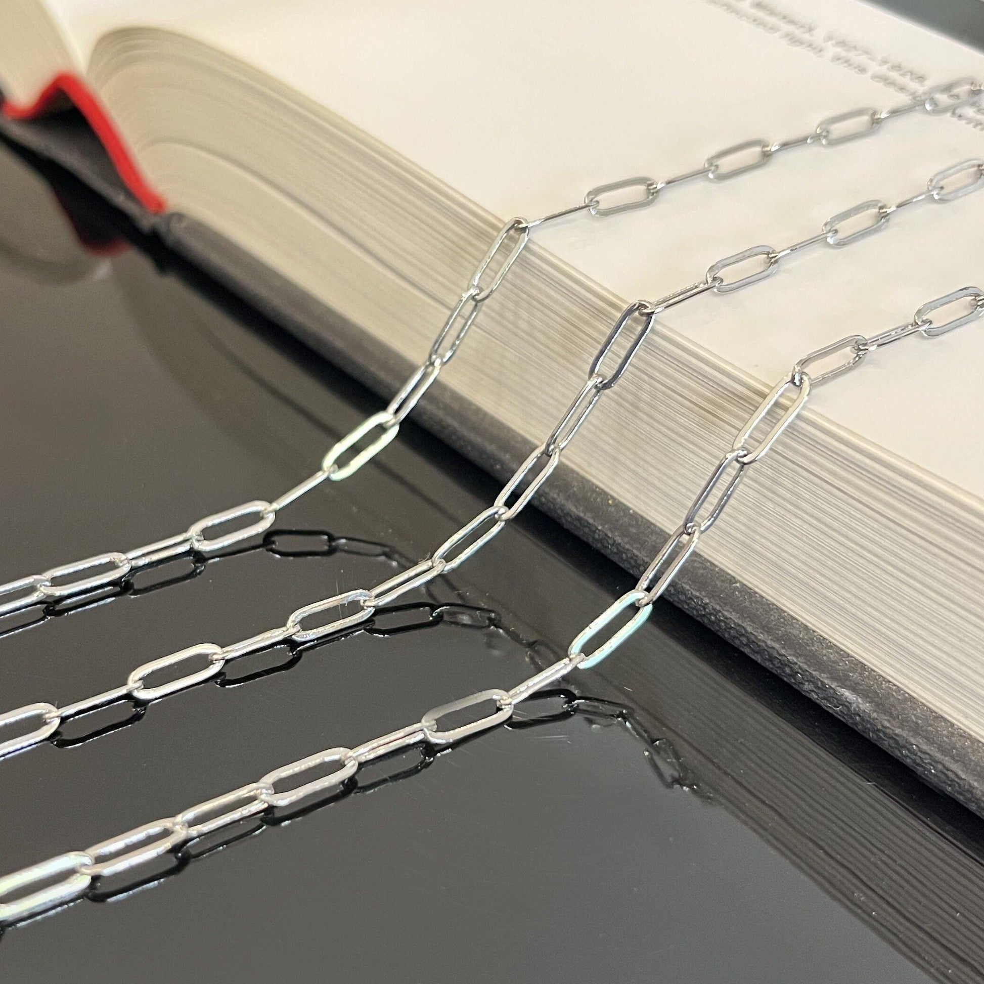 Sterling silver paperclip chain 9x3mm oval links displayed flat showing chain texture