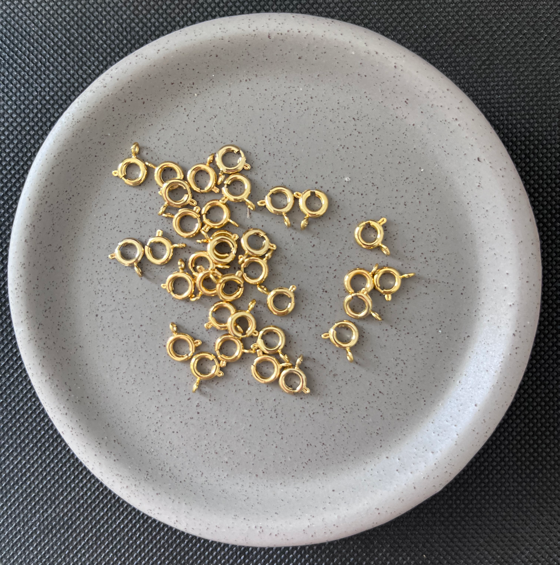 Gold jewelry components on a gray plate