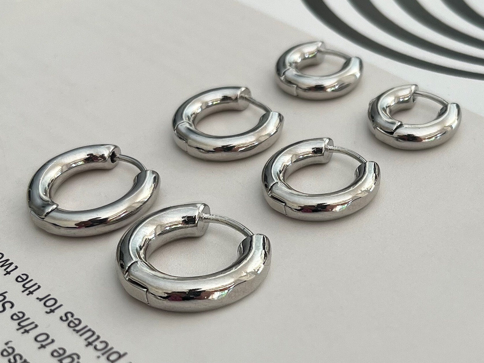 Close-up view of sterling silver huggie earrings showing thickness and quality finish