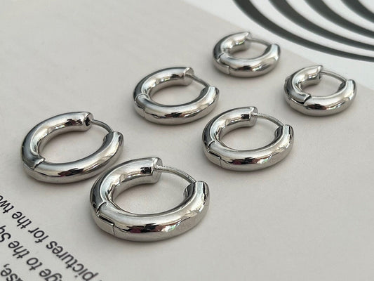 Close-up view of sterling silver huggie earrings showing thickness and quality finish